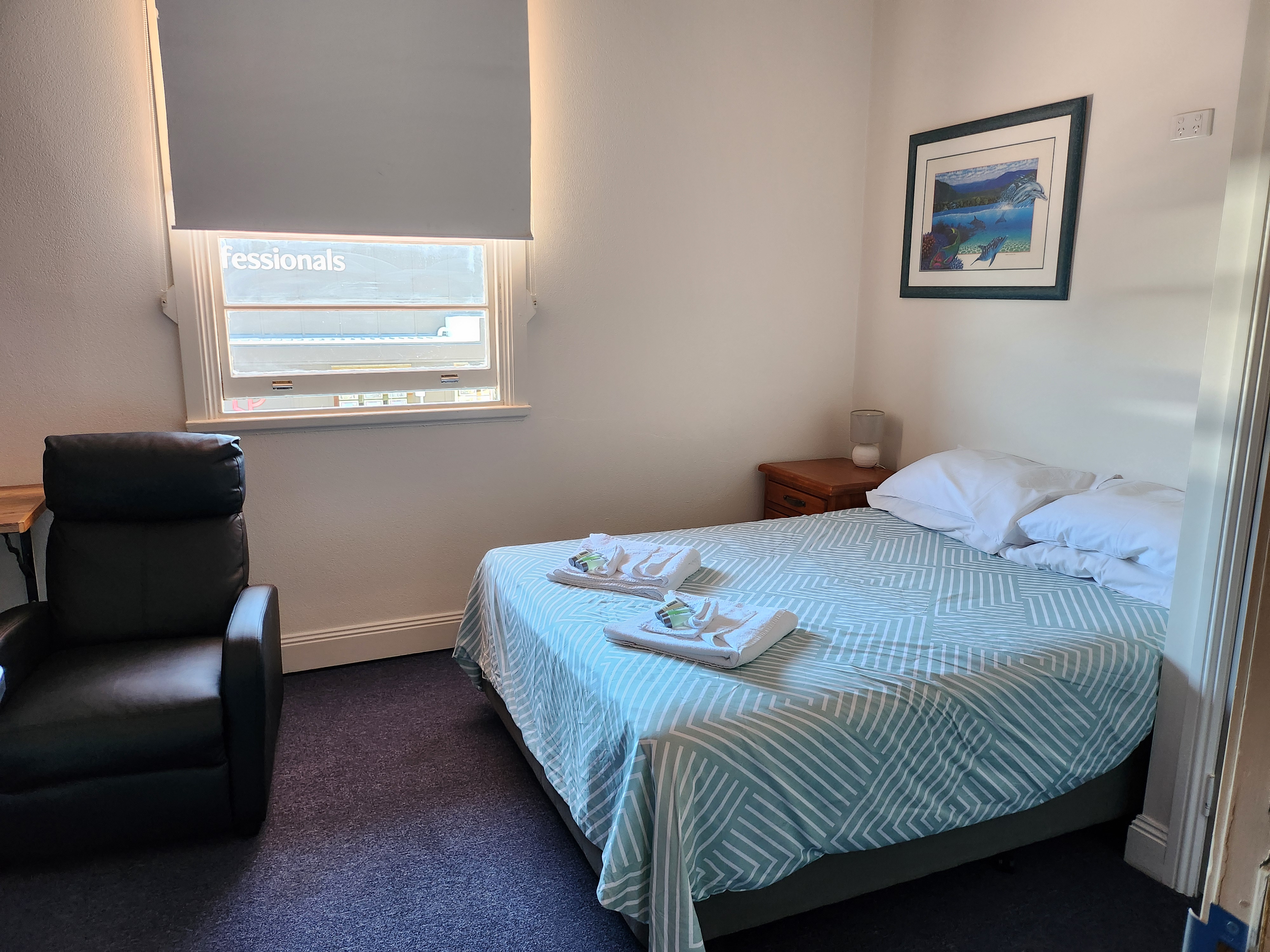 Comfortable queen room with a made bed, fresh towels, and a leather recliner