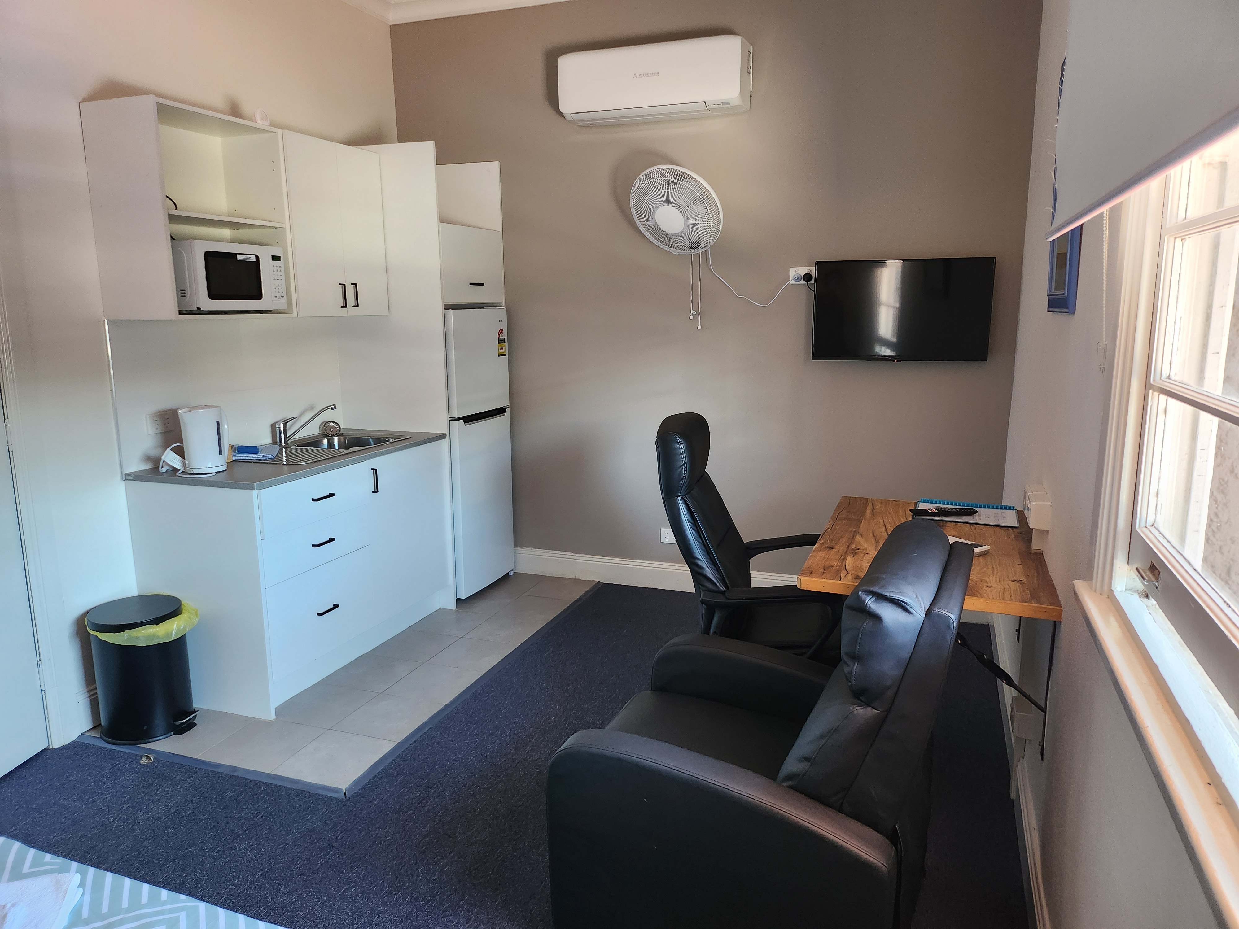Room with kitchenette, smart TV, desk, and seating