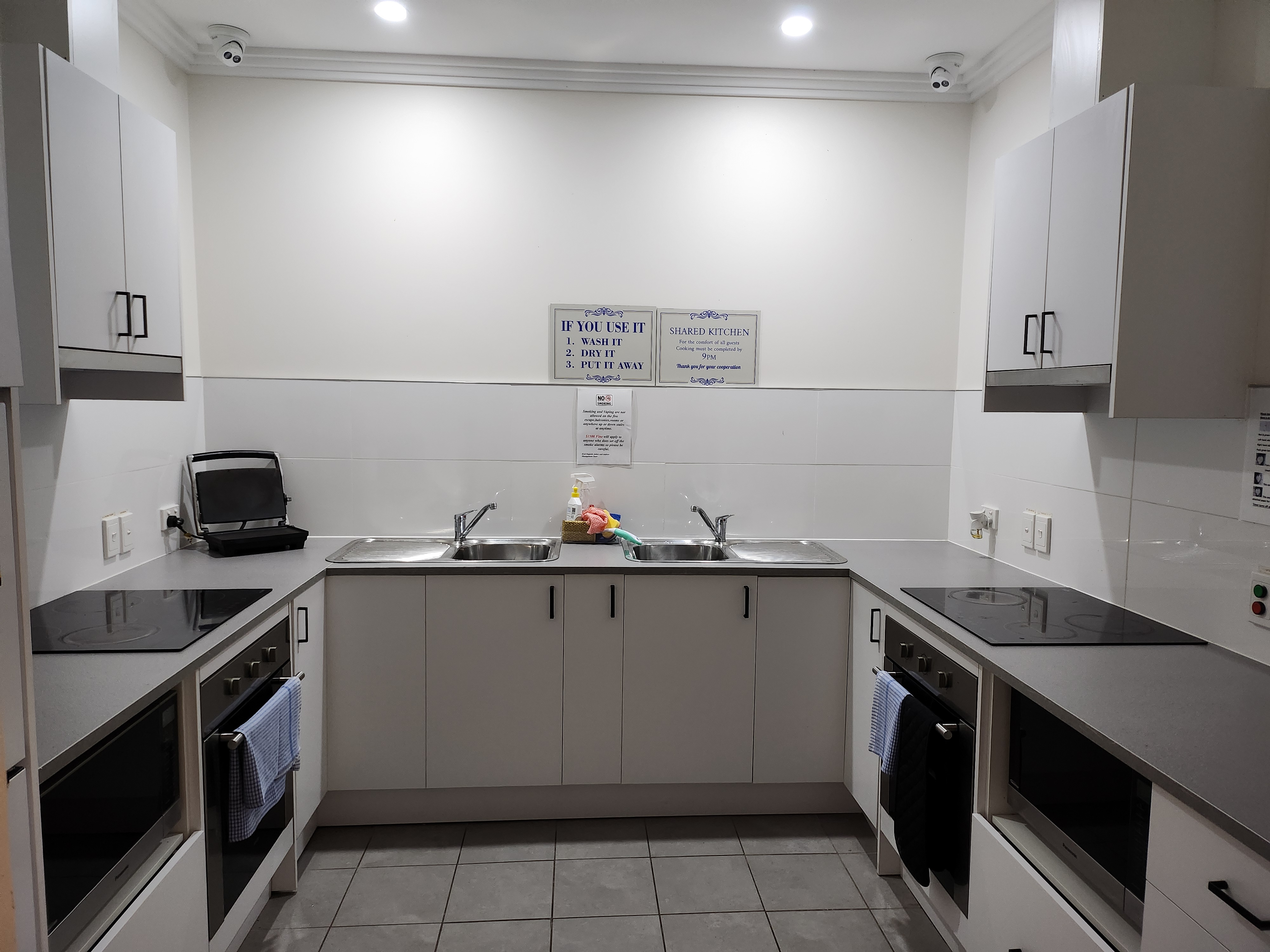 Shared guest kitchen with cooktops, ovens, and twin sinks
